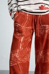 Pantalón relaxed fit de punto ligero tejido en hilatura de algodón color ladrillo con estampado a cuadros difuminados en blanco. Cintura elástica ajustable con cordón y bolsillos laterales.