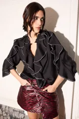 Blusa negra con corte holgado, volados blancos en cuello, mangas y frente, y ajuste en los puños.
