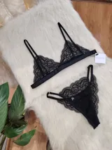 Conjunto de lencería negro de encaje, compuesto por un bralette con breteles regulables y una tanga regulable con corte media less y entrepierna de algodón.