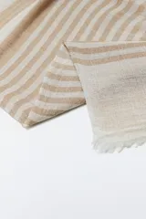Pashmina rectangular de tejido ligero color beige con rayas horizontales color arena y flecos cortos en los extremos.