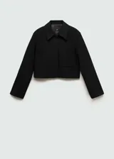 Chaqueta corta negra de corte recto con cuello camisero, manga larga, dos bolsillos de parche delanteros, cierre frontal con botones ocultos y forro interior.