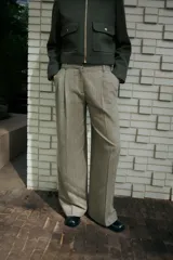 Pantalón de tiro alto con bolsillos delanteros, pinzas y cierre frontal con cremallera y gancho metálico.