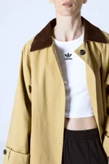 Trench color beige con cuello marrón de pana, doble botonadura y corte clásico.