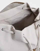 Mochila azul marino con detalles en cuero sintético color camel. Tiene solapa superior con cierre de hebilla, doble bolsillo frontal con hebilla, correa de ajuste y manija superior.