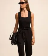 Pantalón negro de sastrería, modelo zanahoria, con tiro alto, cintura elástica con botones y cierre por cremallera. Tiene bolsillos delanteros.