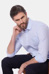 Camisa de lino color beige, de manga larga, con cuello clásico y bolsillo en el pecho.