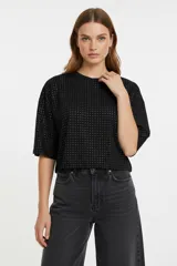 Remera negra de manga 3/4, con cuello redondo y diseño holgado. Presenta un patrón de pequeños puntos plateados (studs) distribuidos por toda la prenda.