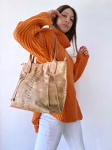 Bolso tipo tote de cuero color camel, con costuras a la vista y tiras de ajuste laterales.