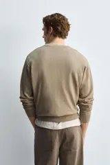 Cárdigan color beige de corte relaxed fit, tejido en hilatura con algodón y ramio. Tiene cuello redondo, manga larga, acabados en rib y cierre frontal de botonadura.