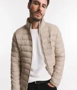 Campera puffer ultraligera color beige, con cuello alto, cierre por cremallera y bolsillos con cremallera. Incluye bolso de almacenamiento.