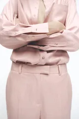 Camisa color rosa de manga larga, con cuello solapa, trabillas en los hombros, bolsillo delantero y cierre frontal con botones.