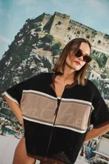 Remera de tejido calado color crudo con rayas horizontales rojas y terminaciones marrones, con cierre frontal y logo bordado.