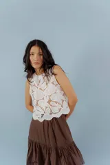 Blusa sin mangas color blanco, con cuello redondo y confeccionada completamente en tejido de encaje con motivos florales.