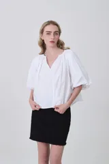 Blusa blanca de algodón con escote en V y frunces en el cuello, mangas abullonadas cortas y calce holgado.