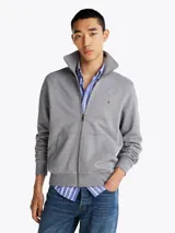 Buzo Tommy Hilfiger de felpa gris con cuello chimenea, cierre de cremallera frontal, bolsillos tipo canguro, puños y bajo de punto canalé, logo bordado en el pecho y corte regular.