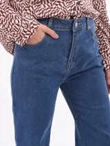 Jean de mezclilla azul de tiro alto, corte acampanado (bootcut) y largo con ruedo deshilachado.