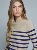 Sweater de tejido de punto color beige con rayas horizontales azules, cuello alto con botones dorados en el hombro.