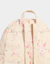 Mochila urbana negra de cuerina con bolsillo frontal con cierre y charm colgante de cadena con dije de corazón y candado. Tiene correas regulables, manija superior, cierre superior, doble bolsillo frontal (uno con charm metálico) y bolsillos laterales.