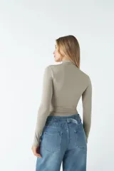 Body negro de poliéster y spandex, con cuello alto tipo polera, mangas largas y frunces laterales.