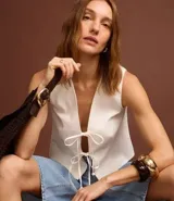 Chaleco blanco sin mangas con lazo delantero.