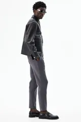 Pantalón de vestir gris oscuro, tobillero, de corte slim fit, con cierre de botón, bolsillos laterales y traseros ribeteados con botón.