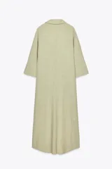 Vestido camisero largo color verde claro, confeccionado en lino. Tiene cuello solapa, escote en V, manga tres cuartos con trabilla y botón, bolsillos delanteros de plastrón, aberturas laterales en el ruedo y cierre frontal con botones.