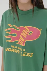 Remera marrón de algodón con cuello redondo y estampado frontal con el logo de la marca Pulau y la frase "Wear More & Worryless".