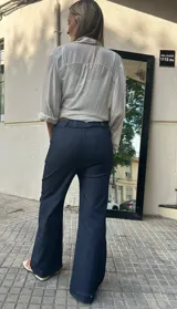 Pantalón de jean de tiro alto, color azul oscuro, de corte ancho y pierna recta. Presenta una pretina ancha y lisa.