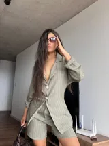 Blazer verde con rayas verticales blancas, de corte holgado, con cuello clásico, cierre frontal con botones y mangas largas.