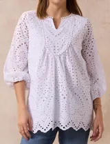 Blusa blanca de algodón con bordado broderie, cuello a la base con escote en V y mangas tres cuartos amplias con puño elastizado.