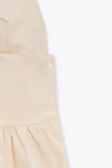 Vestido midi color crema de popelín, con escote en pico, tirantes finos ajustables, bolsillos laterales ocultos y detalle de pliegues. Incluye forro interior.