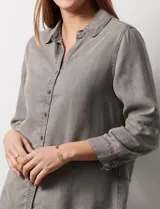 Camisa celeste de tencel con cuello con solapa, escote en V, abertura central con botones y mangas 3/4 regulables con presilla y botón.