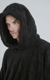 Hoodie negro oversize con cierre central al estilo anorak, confeccionado en piel de corderito sintético. Capucha ajustable con cordón y bolsillo canguro.