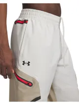 Pantalón cargo Under Armour Unstoppable para hombre, color beige con paneles laterales en marrón claro y detalles en rojo. Confeccionado en tejido técnico resistente al agua, elástico y duradero. Cuenta con bolsillos cargo con cierre y cintura elástica ajustable.