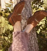 Botas cortas de gamuza color marrón, con cierre lateral y detalle de hebilla metálica.