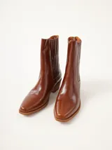 Bota de cuero negro con caña media, punta fina y taco de madera de 5 cm.