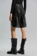 Bermuda de símil cuero brillante color negro, de calce relajado y tiro medio. Presenta bolsillos cargo laterales, bolsillos delanteros, pinzas traseras, presillas y broche delantero.