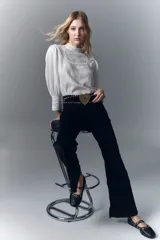 Pantalón de jean negro de pana, de tiro medio, ajustado en la cintura y con pierna levemente acampanada.