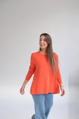 Sweater naranja de tejido de punto, corte recto, cuello redondo y mangas largas. El frente es más corto que la parte trasera y tiene aberturas en la espalda.