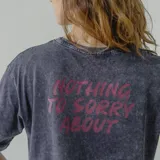 Remera gris con efecto acid wash y estampa en la espalda con la frase 'Nothing to sorry about' en color fucsia.