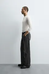 Pantalón de jean celeste de corte flare, con tiro medio, cinco bolsillos, cierre frontal con cremallera y botón, y bajo con acabado irregular.