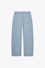 Pantalón de jeans celeste claro, de tiro medio, corte tapered y largo hasta el tobillo. Tiene cinco bolsillos, trabillas en la cintura y cierre frontal con cremallera y botón.