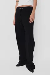 Pantalón de jogging color beige, de frisa y corte relajado. Con cintura de rib al tono, cordones con punteras metálicas y ojalillos personalizados de marca. Detalle de bordado a contratono en ambos laterales de pierna.