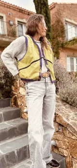 Chaleco color crema con ribete amarillo, de corte recto y sin mangas.