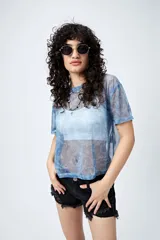 Top translúcido azul con estampado abstracto, de manga corta y tejido liviano con sutil brillo metálico.