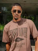 Remera de jersey con efecto teñido y corte holgado. Presenta una estampa frontal con el texto 'Sunset Lover' y 'You're my last sunburn' en color verde.