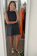 Vestido tejido de manga corta y cuello redondo, color azul oscuro con brillo metálico (lurex). Presenta un corte recto y holgado.