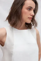 Musculosa de lino color blanco con paneles laterales en color beige, escote redondo y espalda con pliegues y cierre con botones.