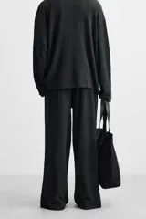 Pantalón negro de corte amplio con cintura elástica ajustable con cordón, bolsillos delanteros y detalle de bolsillo trasero de vivo.
