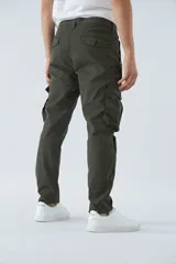 Pantalón cargo color marrón, corte slim, con cierre y botón en la cintura, pasacintos y bolsillos cargo con botones.